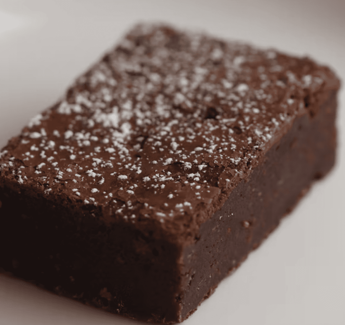 Brownie de chocolate denso con capa crujiente y centro fudgy.