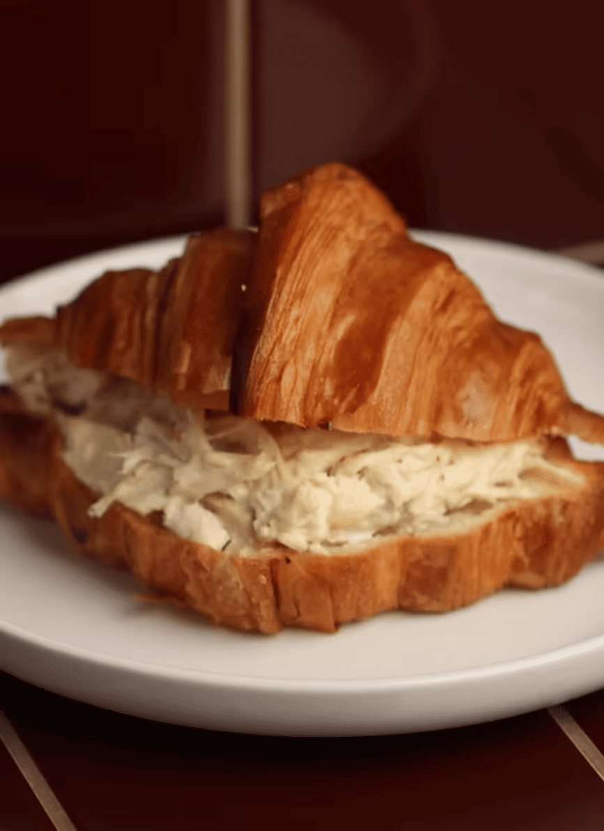 Sánguche de croissant con jamón y queso derretido, opción de mayonesa y mostaza.