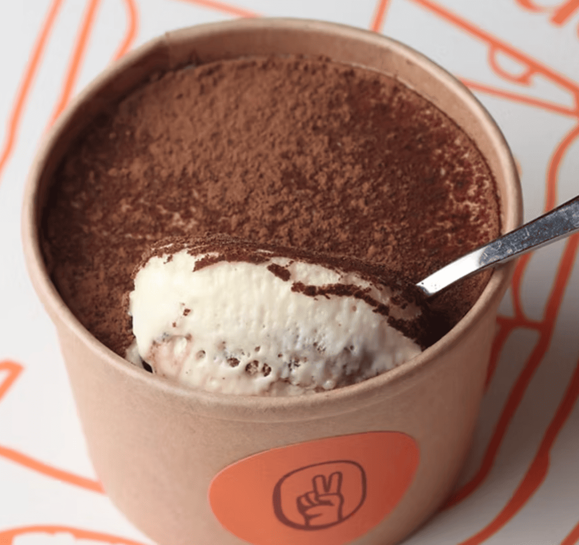 Tarrina de tiramisú con crema de mascarpone, bizcocho de café y cacao espolvoreado.