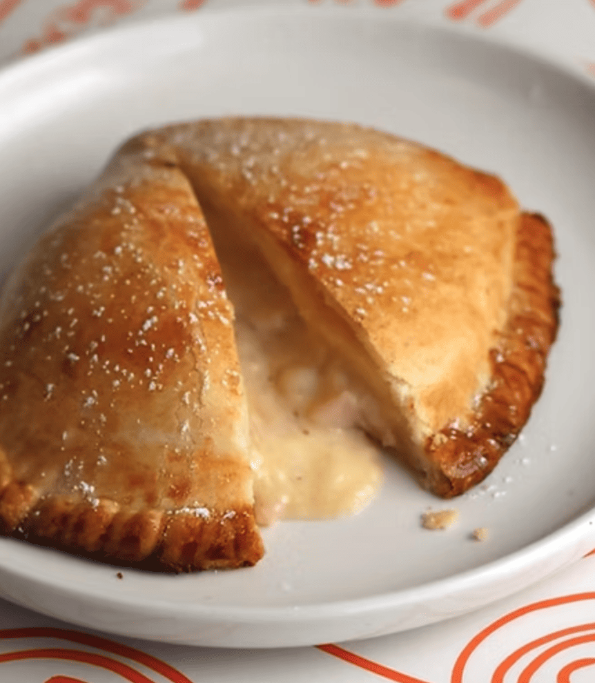 Empanada horneada rellena de jamón, queso derretido y salsa bechamel en masa crujiente.