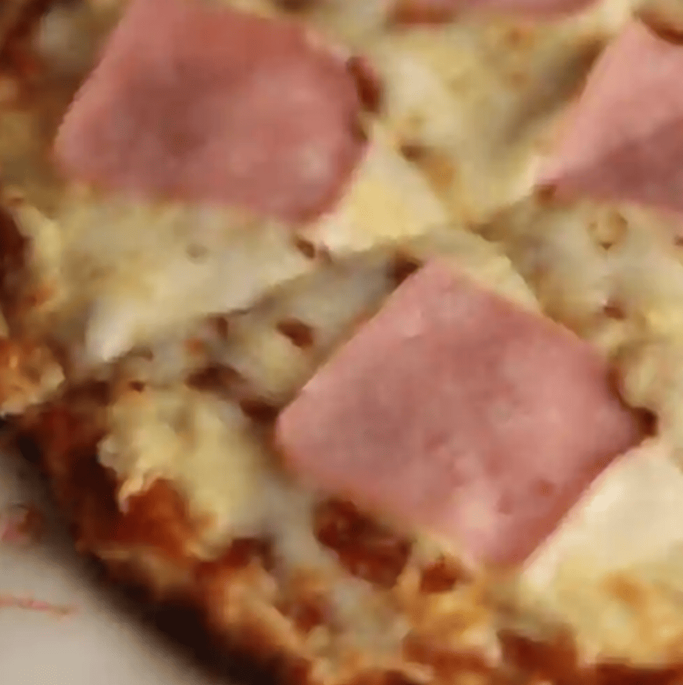 Pizza con salsa de tomate, queso fundido y jamón sobre masa artesanal.