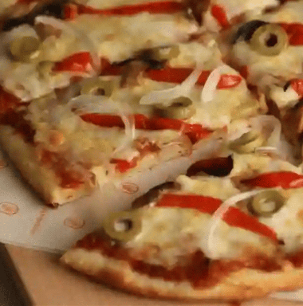 Pizza con pimientos, champiñones, cebolla blanca y aceitunas verdes sobre salsa de tomate y queso.
