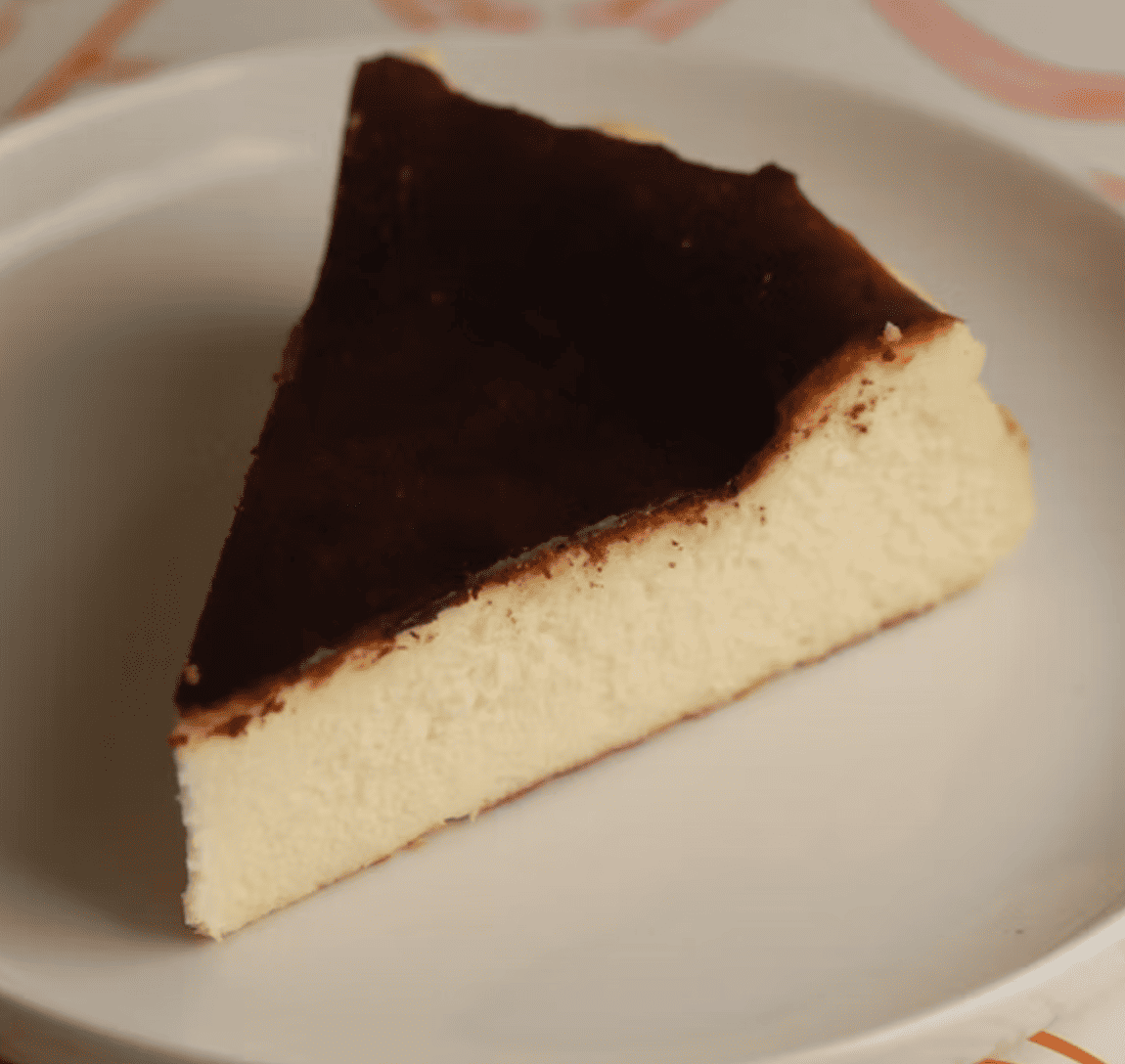 Trozo de tarta de queso vasca con superficie caramelizada y textura cremosa.